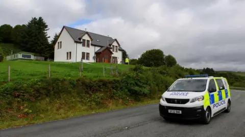 PA Media A constabulary  van parked beneath  a white-walled detached property. A constabulary  serviceman  is adjacent   the house.