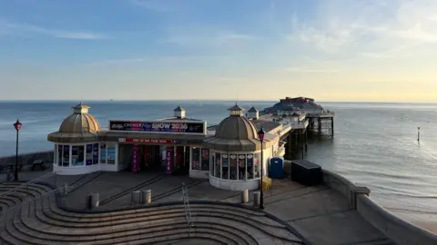 Owen Sennitt/BBC The view of the Victorian pier from above, showing the steps on to it, entrance and theatre in the distance