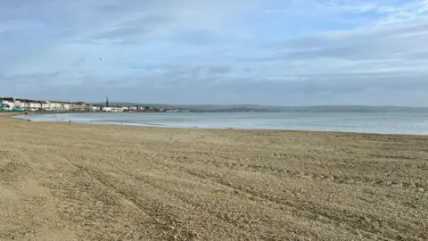 Weymouth Town Council Expanse of golden flat sand at Weymouth after levelling works with the sea to the right.