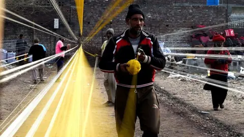 NurPhoto via Getty Images Workers prepare kite-flying thread ahead of the Basant festival in Lahore, Pakistan.
