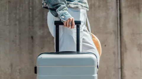 Cropped shot of young woman with suitcase walking