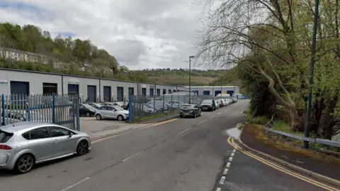 A Google Maps image of the Glandwr Industrial Estate, with trees on one side of a main road and buildings on the other side