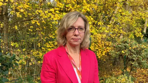 Matt Knight/BBC A head and shoulders picture of Dr Karen Chumbley standing in front of some trees. She is wearing a pink blazer.