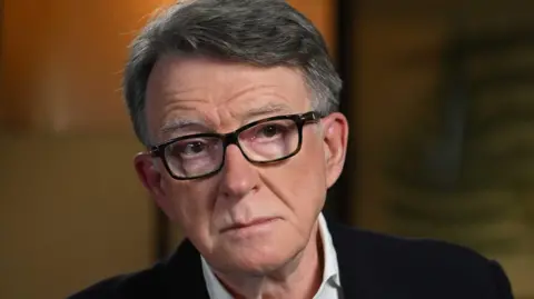 Jeff Overs/BBC Peter Mandelson during an interview with the BBC. He is wearing dark-rimmed glasses and a black suit.