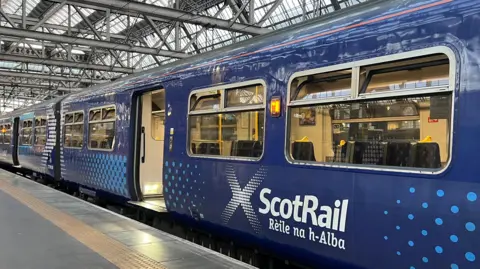 A blue ScotRail train in Glasgow Central at an unspecified platform.