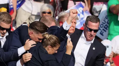 Reuters With blood on his face, former US President Donald Trump raises his fist after the shooting in Butler, Pennsylvania. Photo: 13 July 2024