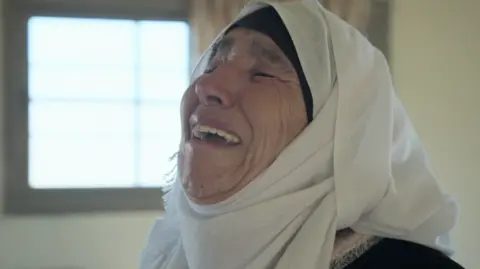 A woman wearing a white headscarf is crying