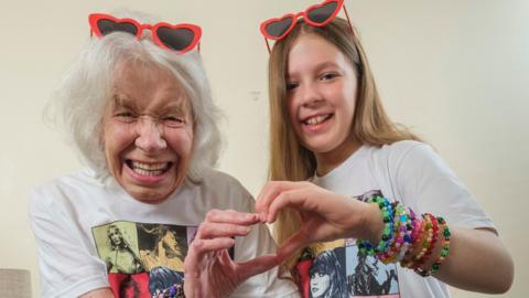 Girl and her great-grandma making a heart shape with their hands