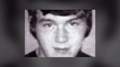 A picture of Eamon Molloy. It is a black and white photograph of a man looking to camera. He has dark hair combed over his forehead.