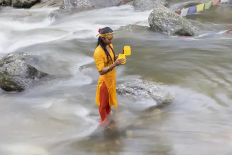 Narendra Shrestha / EPA-EFE A Hindu pilgrim from Nepal takes a holy dip and collects water from the Bagmati River to worship Shiva