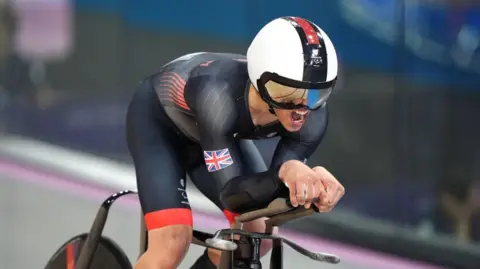 PA Media Great Britain's Archie Atkinson is competing during the Men's C4 4000m Individual Pursuit gold final at the National Velodrome on day three of the Paris 2024 Summer Paralympic Games. He is wearing black Team GB clothing.