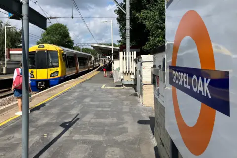View from Gospel Oak station shows passengers awaiting an incoming yellow train (left) and the roundel (right)