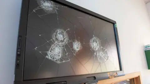 City of Wolverhampton Council A black TV screen on a white wall which has been smashed in several places