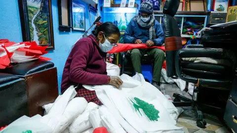 In Kathmandu, Nepal, on February 20, 2026, a Nepali flagmaker prints flags of a political party at his workshop