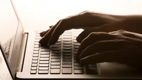Stock image of a woman's hands typing on a laptop.