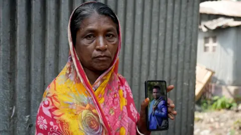 Anahita Sachdev/BBC Shefali Rani Das with a picture of her son, Dipu, in a suit after he got his job