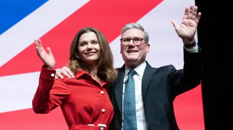 PA Lady Victoria and Sir Keir Starmer waving at the crowd from Labour conference stage