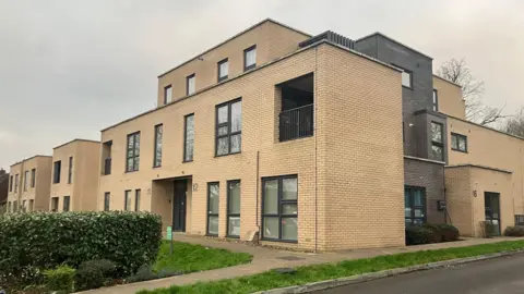 One of the newer social housing block of flats built in Guildford on the Park Barn estate. There is a hedge and a path outside of the front.