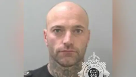 West Mercia Police A mug shot of a bald man who has tattoos on his neck. He is staring into the camera with a straight face. Half of the West Mercia Police logo is visible at the bottom of the mug shot. 