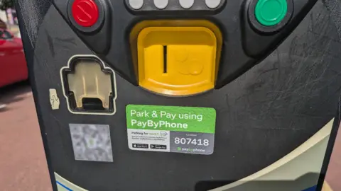 Leicester City Council The front of a car park pay and display machine with a QR code sticker attached next to the official signage
