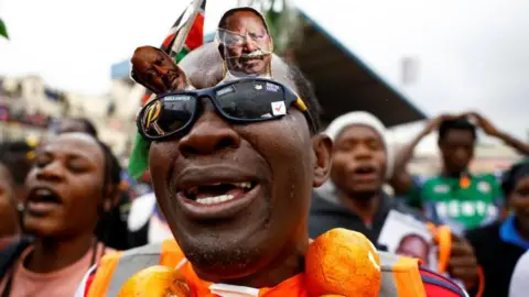 Reuters A crying mourner wearing black glasses mounted with Raila Odinga's portraits