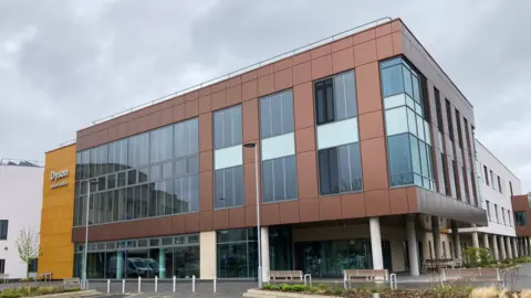 The Dyson Cancer Centre completed from the outside, three levels in modern design, copper-coloured panels on the walls