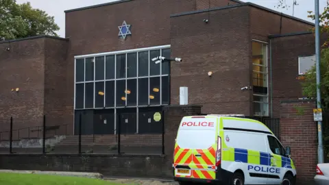 Reuters Police van parked in front of the gates of the multi-storey brick-built synagogue, which has a six-pointed Star of David above large windows.
