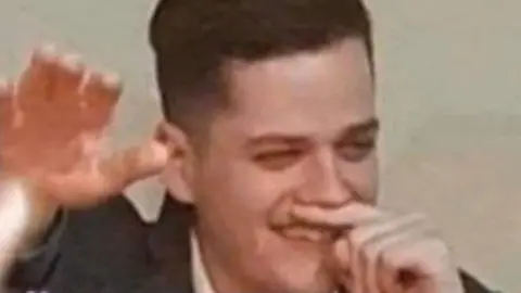 A man with his right arm in the air and a finger under his nose