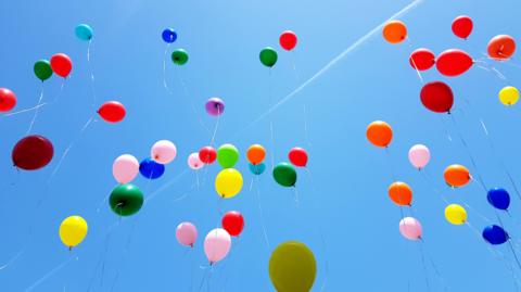 Colourful balloons rising into a blue sky