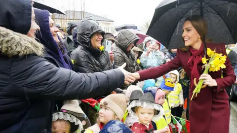 Reuters Princess Catherine greeting crowds and shaking hands with members of the public whilst holding a bunch of daffodils