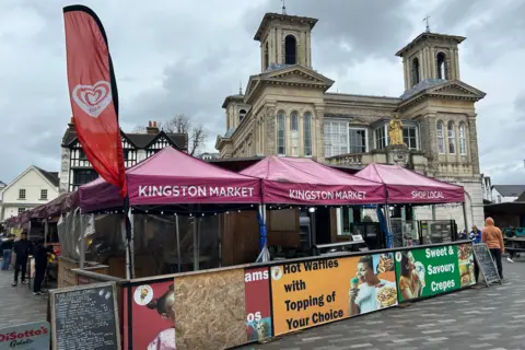 LDRS Kingston Market signs on stalls offering waffles and crepes in front of a grand market house under grey skies