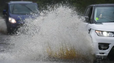 Vehicles travel through areas of flooding.