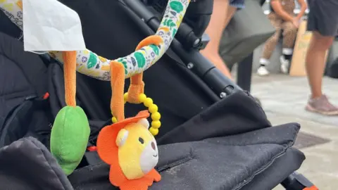 George Carden/BBC An empty pram with colourful toys hanging down 