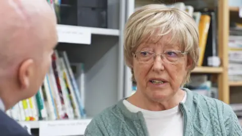 Anne Pack talking to Glenn Campbell. She is wearing a green cardigan and a white top.