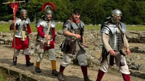 The four men dressed as Roman soldiers walking along Hadrian's Wall