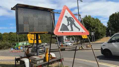 A large roadworks sign and digital display next to a road