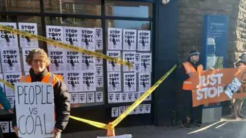 Just Stop Oil Protesters holding posters outside Mark Jenkinson MP's office on Friday morning