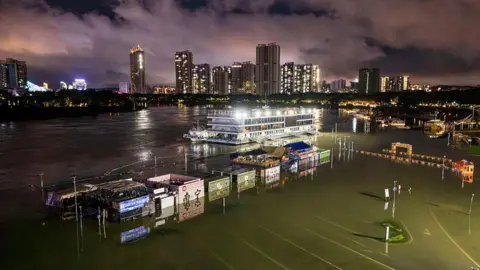 Getty Images A flooded riverside walkway and shops are seen near a wharf on the Yongjiang river in Nanning, in China's southern Guangxi region