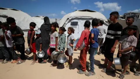 Reuters Displaced children queue for food at a charity kitchen in Gaza City