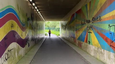 Lone woman walking through an underpass.