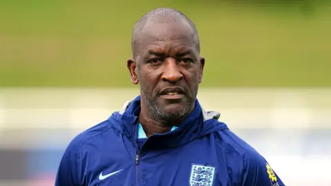 PA Media Chris Powell looking at the camera and wearing a royal blue sports hoodie, with the 3 Lions logo and a Nike logo on the opposite side. He is bald with very light stubble.