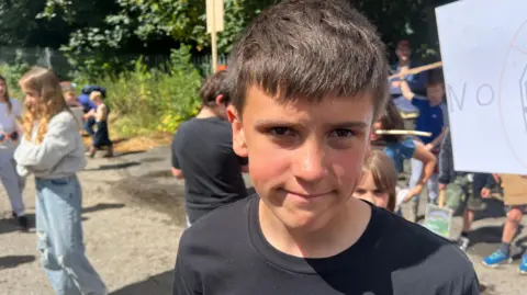 Ruben wearing a black t-shirt standing near other children outside.