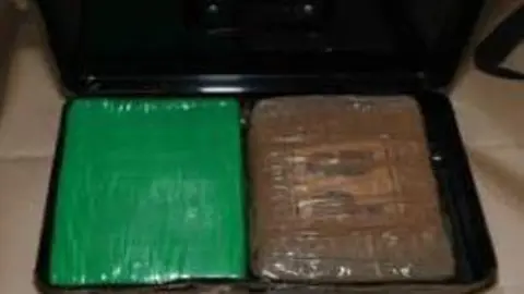 Police handout Two blocks of cocaine - one wrapped in green plastic, the other in a brown container - are on display in a photograph released by police.