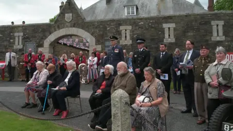 People, some sat and some stood, bowing their heads in a moment of silence.