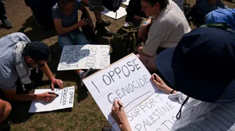Reuters People prepare signs at a protest against the ban of Palestine Action