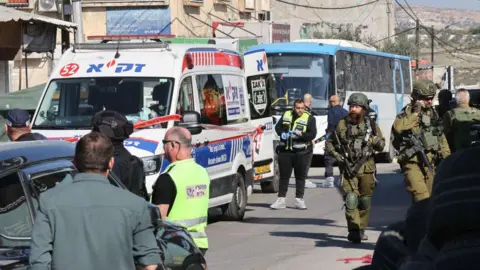 AFP Israeli soldiers and paramedics at the scene of a deadly shooting attack on a bus and other vehicles in the village of al-Funduq, in the occupied West Bank (6 January 2025)