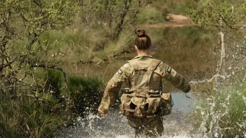 Lt Fisher makes a splash as she enters Peter's Pool which is a body of water in the woods on the marine's Endurance Course at Woodbury Common