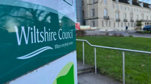 A close-up of a Wiltshire council logo on a sign just outside it's headquarters
