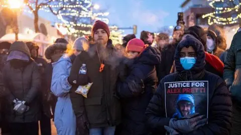 People mourn at a memorial in the area where 37-year-old Alex Pretti was shot dead by federal immigration agents earlier in the day in Minneapolis, Minnesota, on January 24, 2026. 