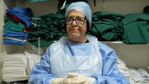 Marta Cohen standing wearing hospital scrubs and PPE in the children's mortuary.